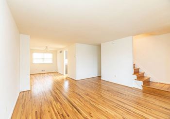an empty living room with a hard wood floor and white walls